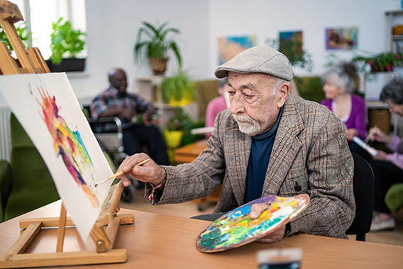 senior man painting on canvas