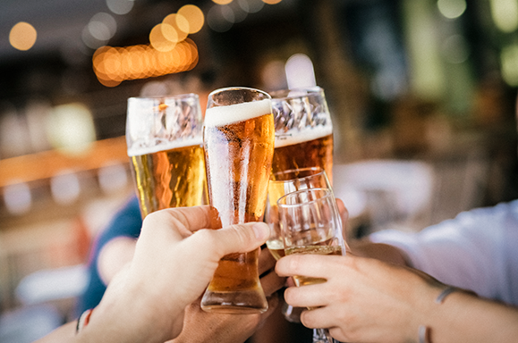 hands with pint glasses of beers doing a toast