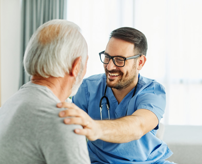 male nurse smiling with hand on shoulder of senior man